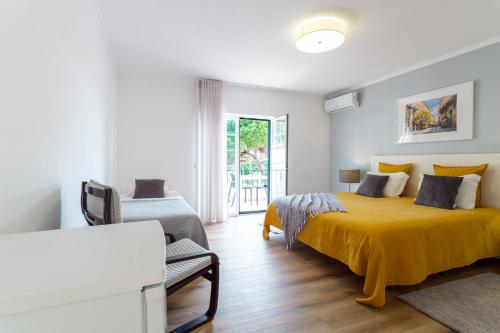 a white bedroom with a yellow bed and a window at Moro's Friends House - Cascais in Cascais