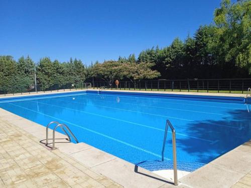 Una gran piscina azul con árboles al fondo. en Casa Ledo, en Casas de Don Antonio