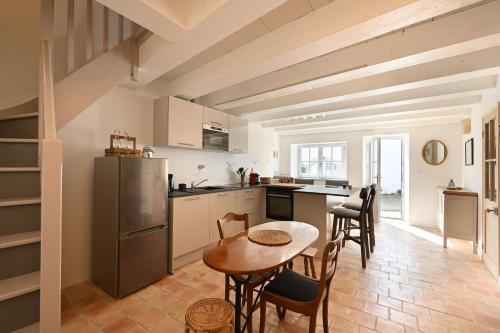 une cuisine avec une table, des chaises et un réfrigérateur dans l'établissement Le Chai Elégant, à Sainte-Marie de Ré