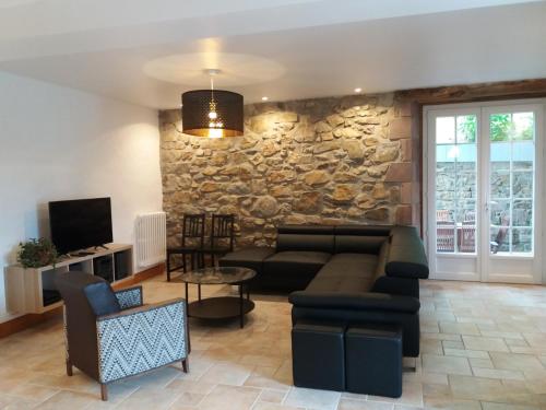 un salon avec un canapé et un mur en pierre dans l'établissement Kalonjania, à Saint-Martin-dʼArrossa
