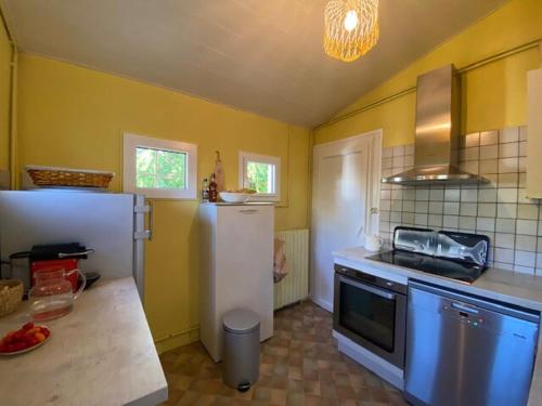 une cuisine avec un réfrigérateur blanc et des murs jaunes dans l'établissement Maison au calme à Gujan Mestras, à Gujan-Mestras