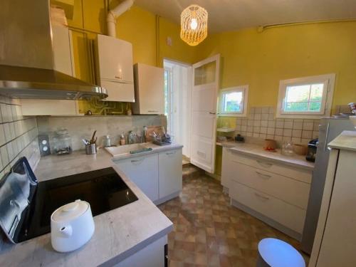 une grande cuisine avec des murs jaunes et des armoires blanches dans l'établissement Maison au calme à Gujan Mestras, à Gujan-Mestras