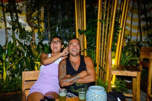 two men sitting on a bench talking on a cell phone at Happy Bear Hostel Phu Quoc in Phu Quoc