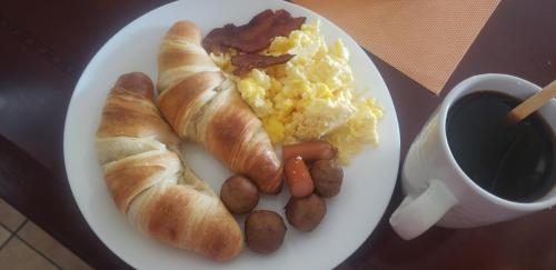 a plate of eggs sausage and croissants and a cup of coffee at Vingåker Hotell in Vingåker