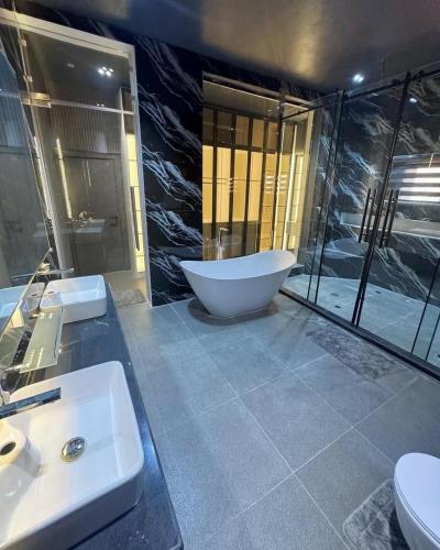 a bathroom with a tub and two sinks and a toilet at Luxury 3 bedroom gwarinpa in Abuja