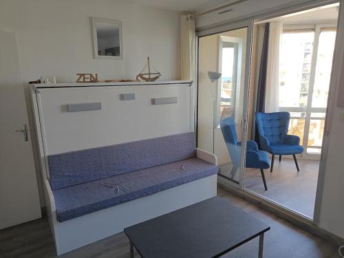 - un salon avec une grande cheminée et une chaise bleue dans l'établissement Studio cosy vue mer, à Canet