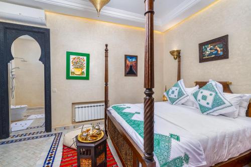 a bedroom with a four poster bed and a bathroom at Riad Diamond Of Marrakech & Spa in Marrakech