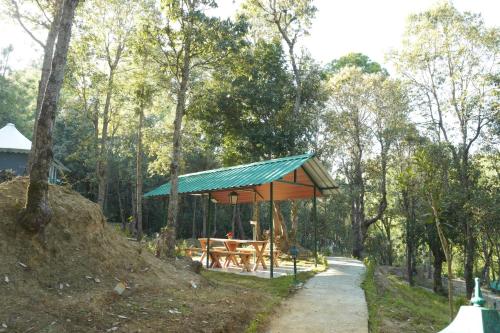 a picnic shelter with a picnic table in the woods at Deodar I Luxury Tent Retreat in Majkhali in Chaubattia