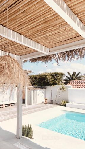 une terrasse avec une piscine sous un parasol en bois dans l'établissement Maison atypique, à Anglet