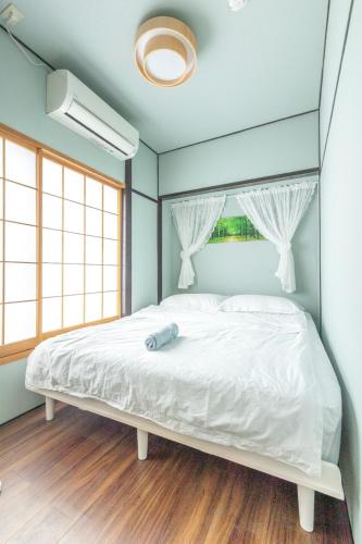 a bedroom with a white bed with a blue wall at Jazz Cat- Japanese Style House, 1Min to sta- 5 Lines Access- Direct to Shinjuku & Shibuya&Akihabara in Tokyo