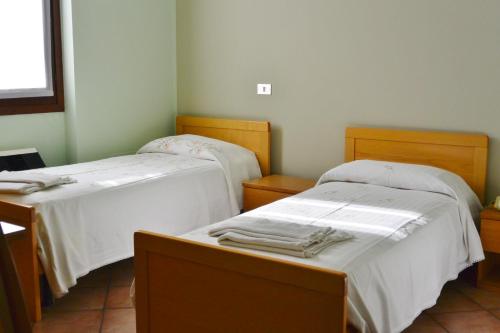 Habitación con 2 camas y sábanas blancas. en Albergo Escondido, en Soresina