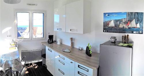  La cuisine est équipée de placards blancs et d'un réfrigérateur. dans l'établissement Mer en Vue - 2 Chambres- 4 Personnes, à Fécamp