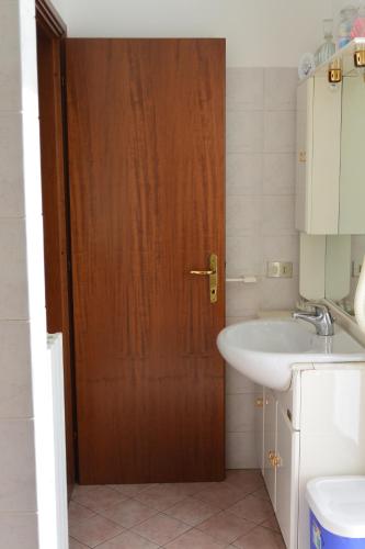 a bathroom with a wooden door and a sink at Albergo Escondido in Soresina