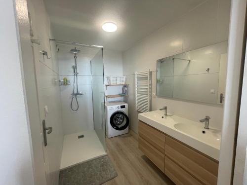 ein Badezimmer mit einer Dusche, einem Waschbecken und einer Waschmaschine in der Unterkunft L'air Marin Clim&Parking in Sète