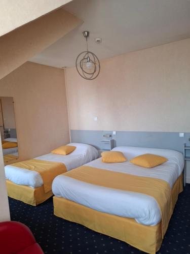 two beds in a hotel room with yellow pillows at Logis Hôtel & Restaurant de la Barque in Beaumont-sur-Sarthe