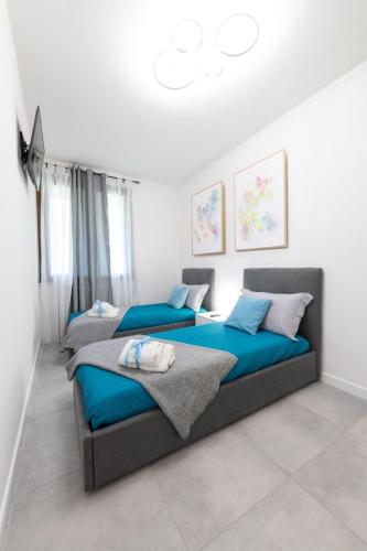 two beds in a bedroom with blue sheets at Apartment24 in Colle di Val d'Elsa