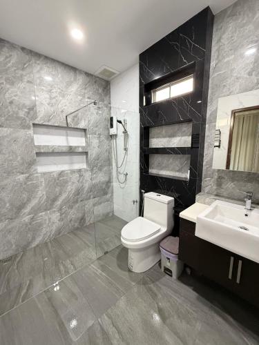 a bathroom with a toilet and a sink and a shower at The Wing Pool Villa Surin in Surin