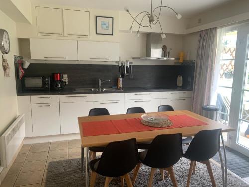 una cocina con armarios blancos y una mesa de madera con sillas. en Appartement-De Haan- Parc Atlantis-Dahlia, en De Haan