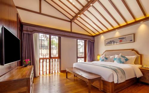a bedroom with a bed and a flat screen tv at Nanxun Boyang New Century Mingting Resort Hotel in Huzhou