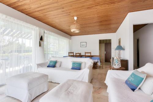 Elle comprend un salon doté d'un mobilier blanc et d'un plafond en bois. dans l'établissement Villa pour 9 sur le Port de Taussat avec piscine, à Lanton