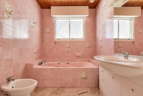 La salle de bains rose est pourvue d'une baignoire, d'un lavabo et de toilettes. dans l'établissement Villa pour 9 sur le Port de Taussat avec piscine, à Lanton