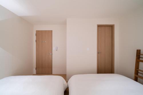 two beds in a room with white walls and wooden doors at Trip made in Busan