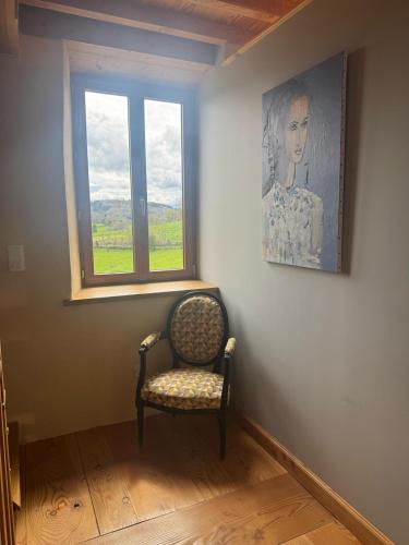 a chair in a room with a painting and a window at La Petite Toscane d'Auvergne in Isserteaux