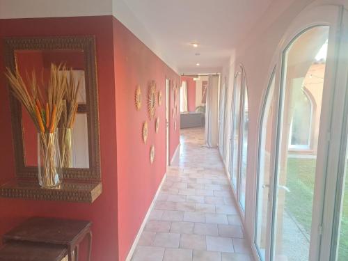 a hallway with red walls and a vase with flowers at Magnifique Villa avec piscine in Cadenet
