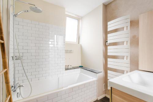 a white bathroom with a tub and a sink at La Fabrique à Souvenirs in Saint Malo