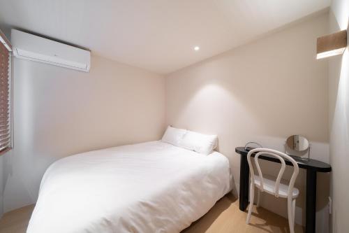 a small bedroom with a white bed and a chair at Trip made in Busan