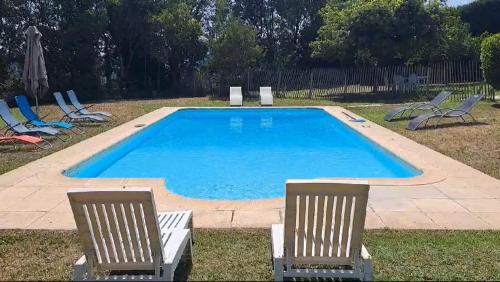 a swimming pool with two lawn chairs and a group of chairs at Magnifique Villa avec piscine in Cadenet