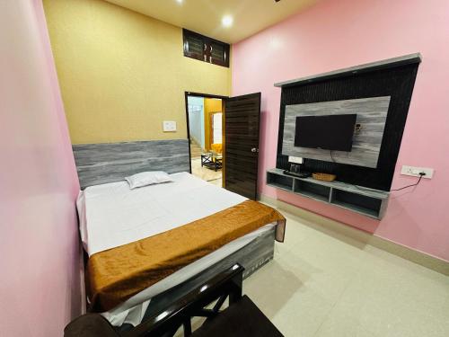 a bedroom with a bed and a flat screen tv at SK Luxury Homestay in Sivasagar