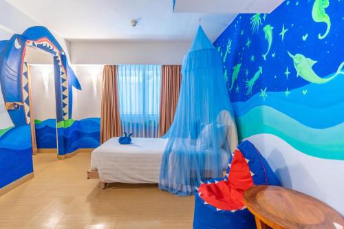 a room with a bedroom with a bed and a mural at Kuta Beach Hotel in Kuta