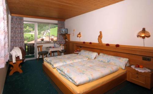a bedroom with a large bed and a kitchen at Hotel Garni Maximilian in Zell am Ziller