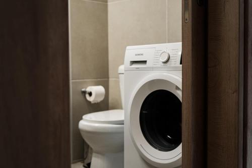 a bathroom with a washing machine next to a toilet at StelAnna-Apartments in Rethymno Town
