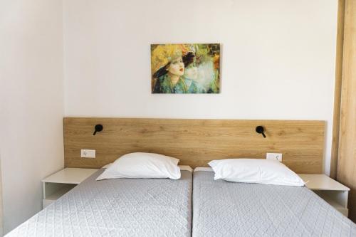 two beds in a bedroom with a painting on the wall at StelAnna-Apartments in Rethymno Town