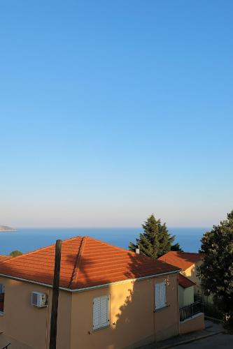 a building with an orange roof with the ocean in the background at Marily's seaview suite with private JACUZZI and BBQ in Spartia
