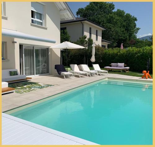 - une piscine dans une cour avec des chaises et un parasol dans l'établissement Villa Soléa I Veigy-Foncenex, à Veigy-Foncenex