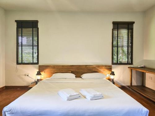 a bedroom with a large white bed with two towels on it at NernJamsai in Sop Poeng