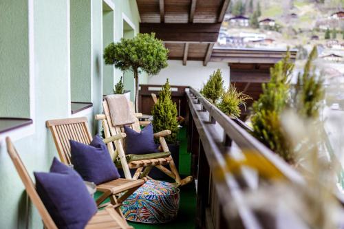 a balcony with chairs and potted plants on a building at Eschenhof Bed & Breakfast in Kaprun
