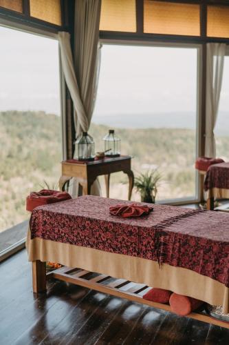 a bedroom with a bed and a large window at Munduk Heaven Luxury Villas in Munduk
