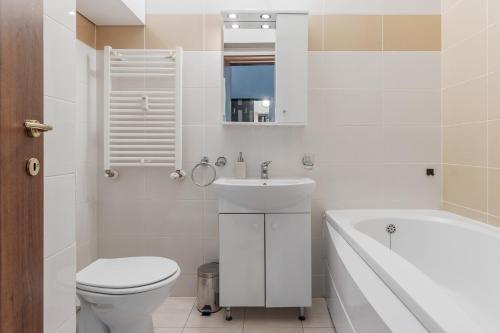 La salle de bains blanche est pourvue de toilettes, d'une baignoire et d'un lavabo. dans l'établissement Lime Light Retreat, à Oradea