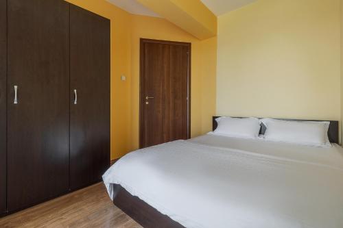 - une chambre avec un grand lit blanc et des placards en bois dans l'établissement Lime Light Retreat, à Oradea