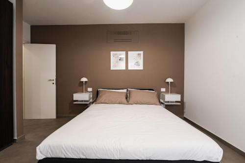 Un dormitorio con una gran cama blanca con dos lámparas. en Design apartment Pescara center, en Pescara