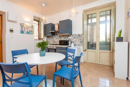a kitchen with a white table and blue chairs at Civico 1 Apt - Acireale in Acireale