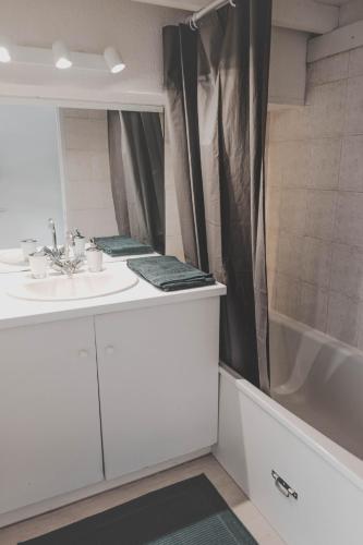 une salle de bain avec un lavabo, une baignoire et un miroir dans l'établissement Appartement Port de Capbreton Hossegor, à Capbreton