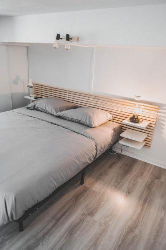 une chambre avec un grand lit avec une tête de lit en bois dans l'établissement Appartement Port de Capbreton Hossegor, à Capbreton