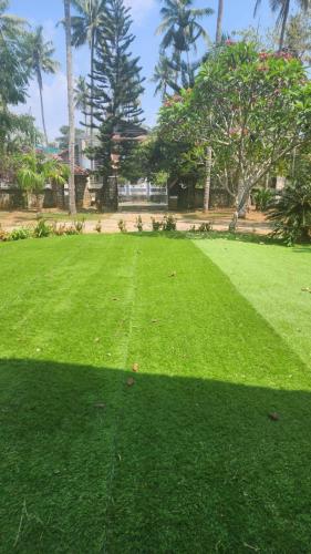 a field of green grass with trees in the background at The Palmyra Estate - by Cocoon, A Luxury Party Villa near Varkala in Paravūr