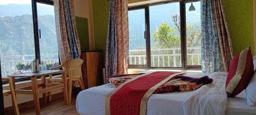 a bedroom with a bed and a table and a window at Birds Hill View Homestay in Nainital