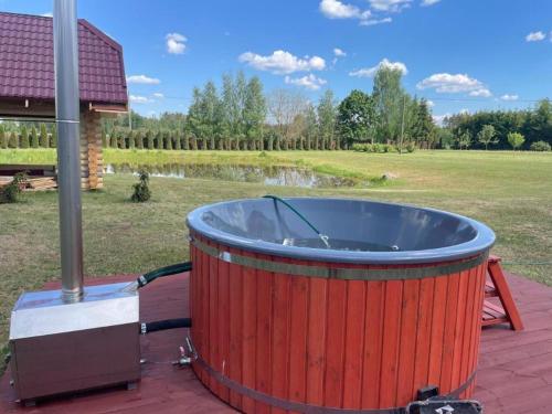 a large red hot tub on a patio with a field at Jaunkades in Grundzāle